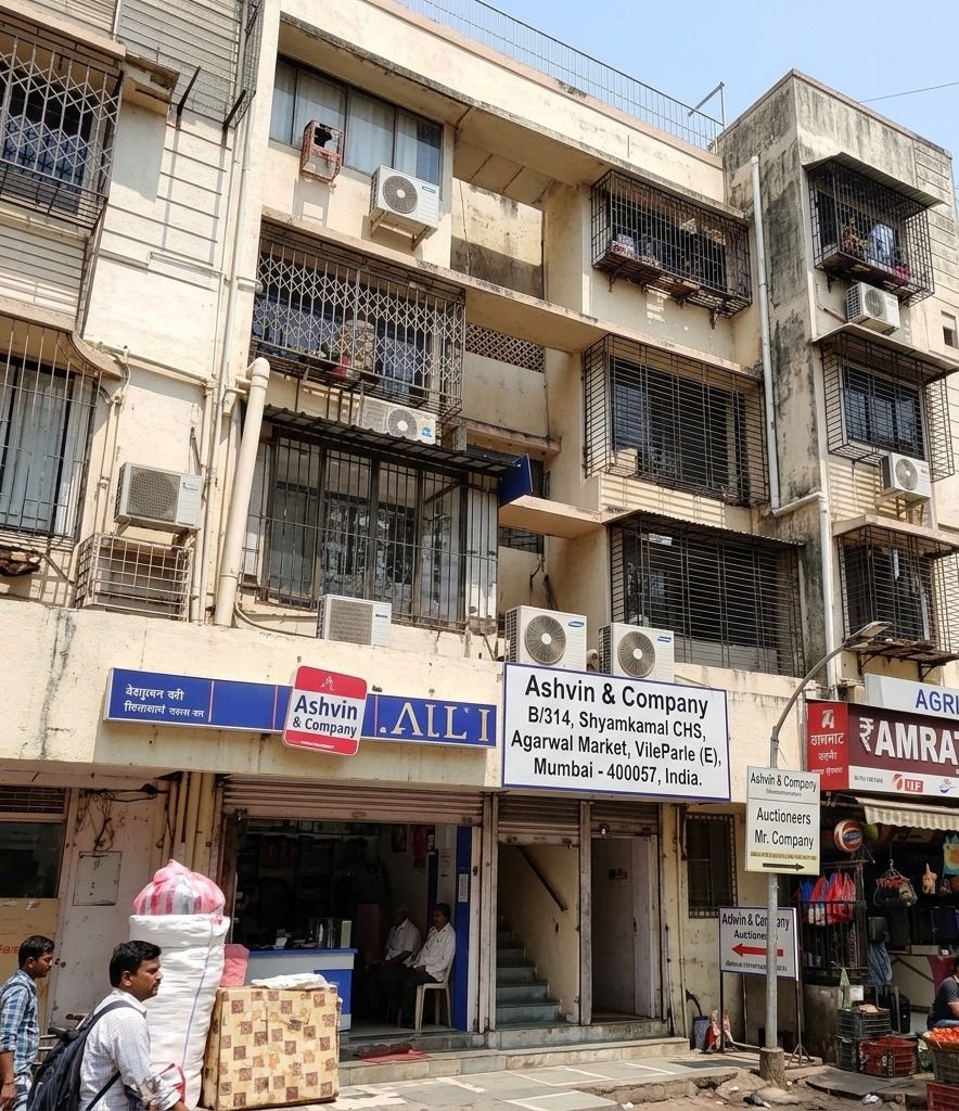 Exterior view of a multi-story commercial building featuring the office entrance and signboard for Ashvin & Company at B/314, Shyamkamal CHS, Agarwal Market, Vile Parle (E), Mumbai.