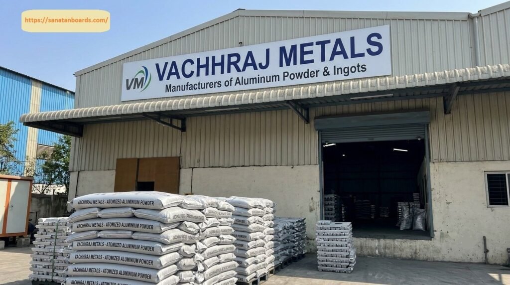 Exterior view of the Vachhraj Metals facility displaying stacked bags of atomized aluminium powder outside a corrugated metal warehouse entrance with company signage.